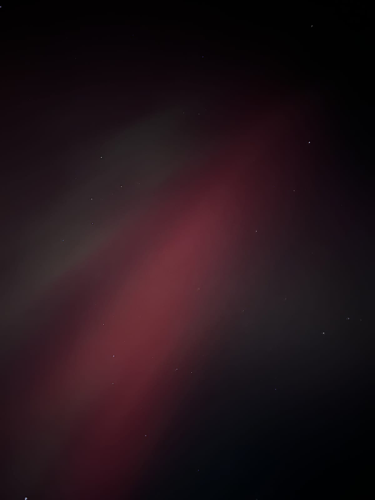Looking straight up into a band of red aurora among the stars.