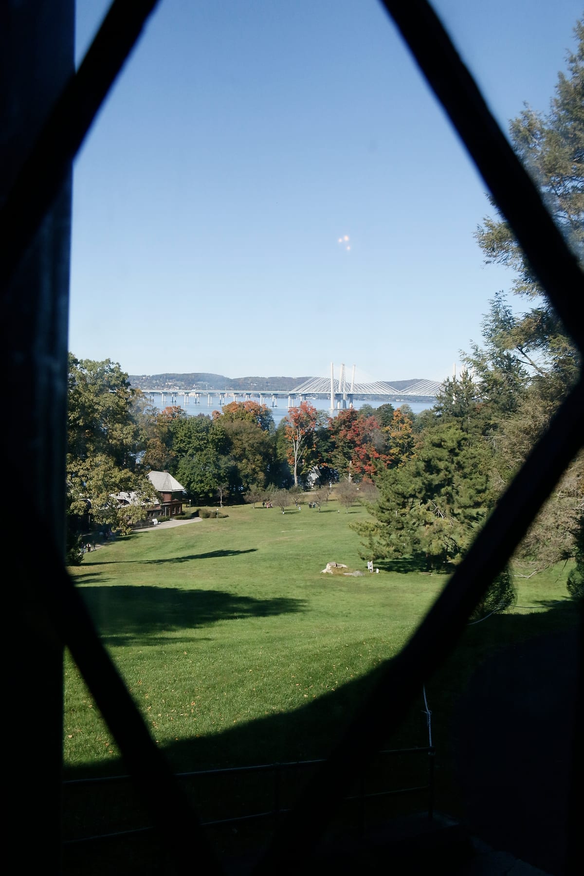 A lawn, trees and the river seen through a diamond-paned window.