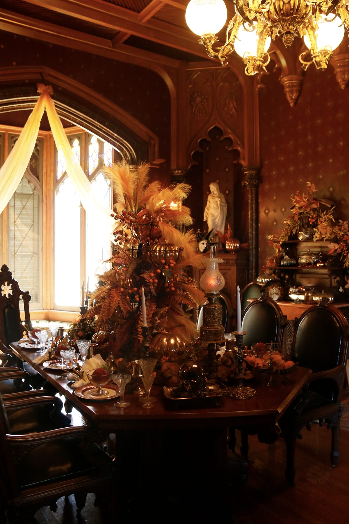 A Gothic dining room with chandeliers and an autumn table.