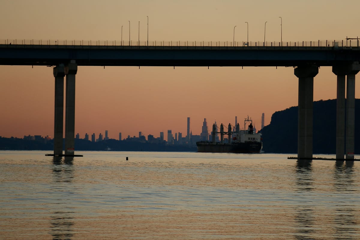 The bridge at dusk, a ship and a distant skyline beneath it.